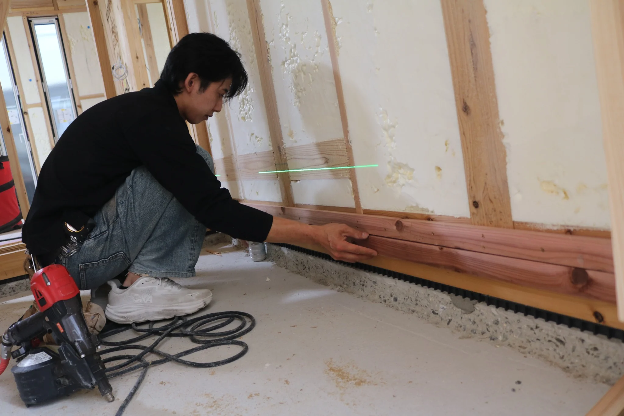 実際の木造住宅施工現場で下地材の納まりを確認する職人