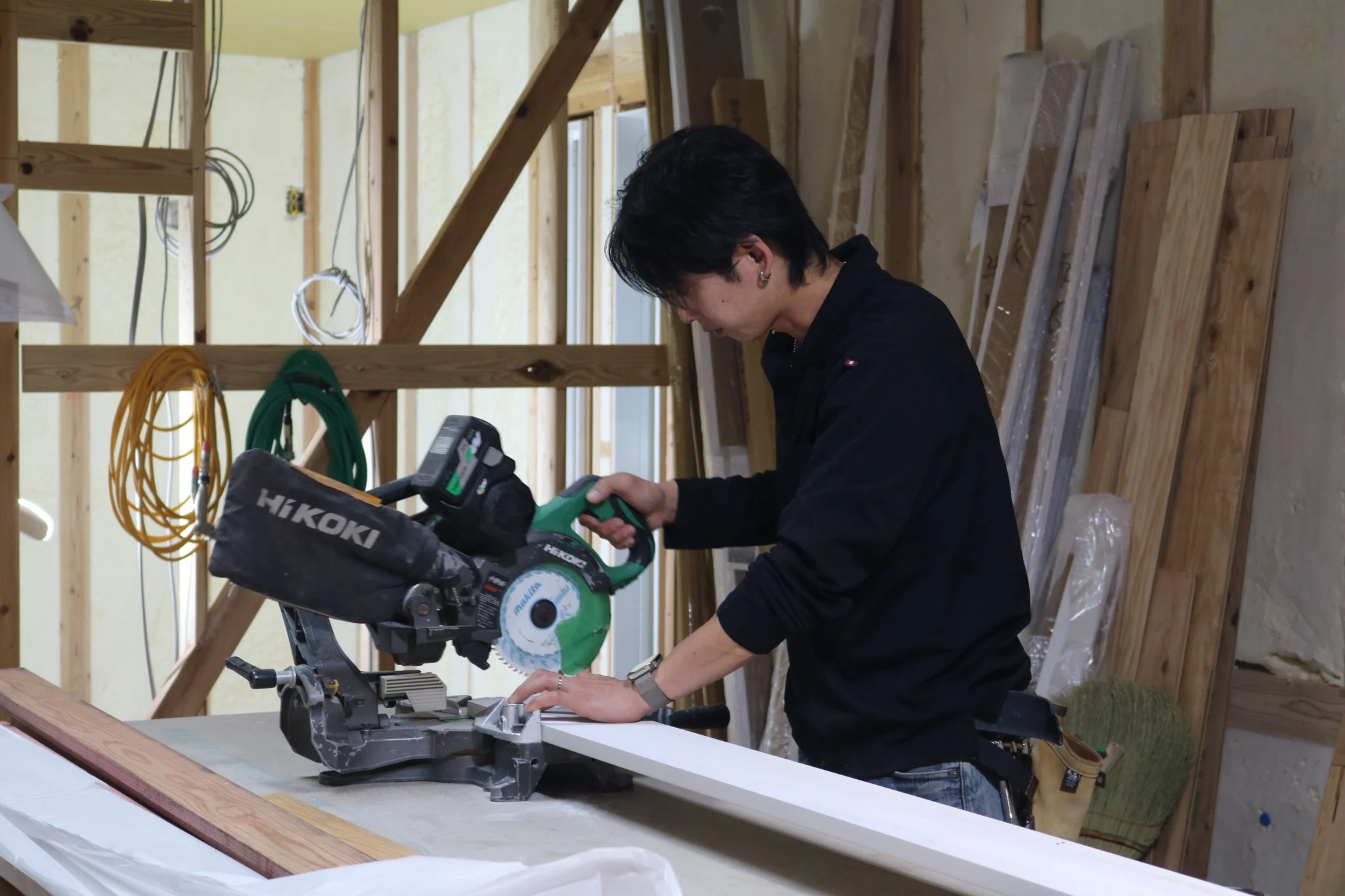 実際の住宅施工現場で卓上丸ノコを使い木材を加工するClear Linkの職人